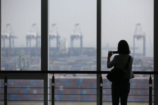 epa03923620 A picture made available on 25 October 2013, shows a woman taking pictures at the Nansha port in Guangdong province, China, 24 October 2013. Nansha belongs to Guangzhou port, which is the country's fourth largest port after Shanghai, Shenzhen and Ningbo, and the seventh in the world. Nansha port has more than 1,200 workers handling 12.2 million TEU (twenty-foot equivalent unit) containers per year.  EPA/DIEGO AZUBEL